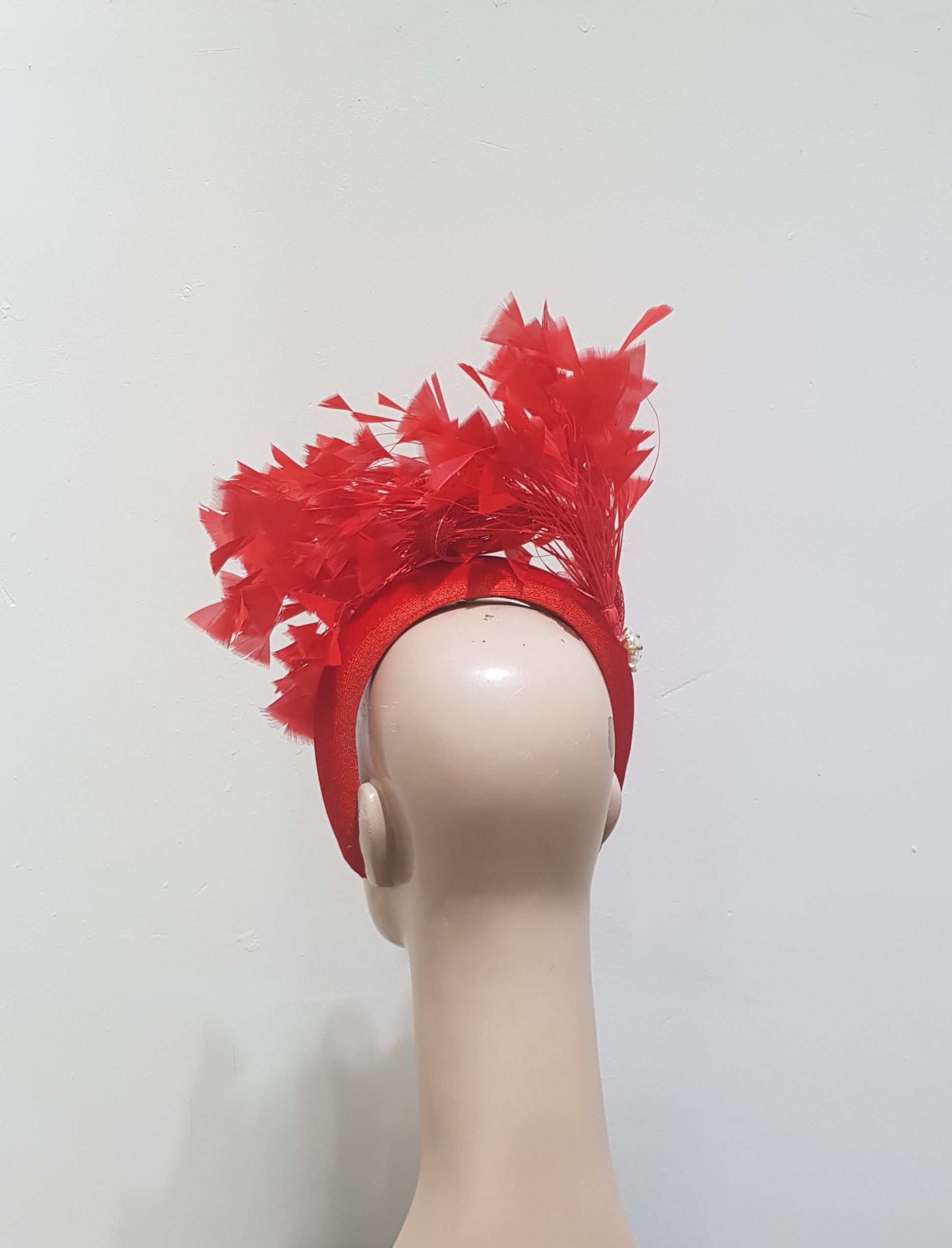 "Feather cluster on a padded headband with sinamay loops around the feathers"