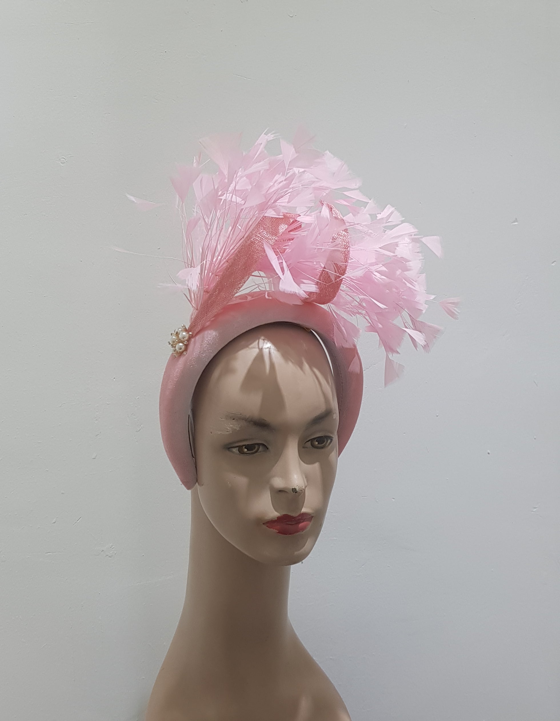 "Feather cluster on a padded headband with sinamay loops around the feathers"