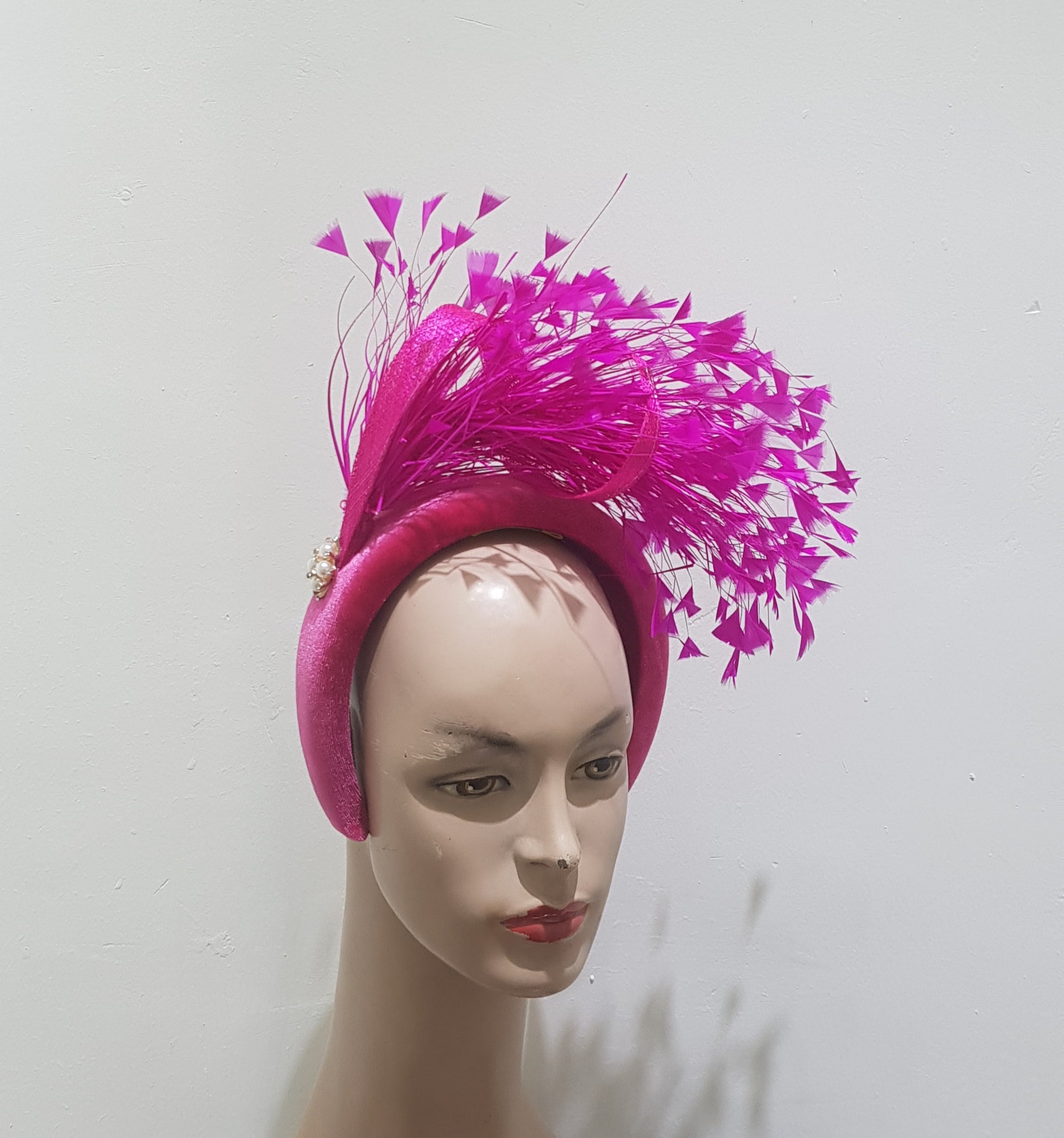 "Feather cluster on a padded headband with sinamay loops around the feathers"